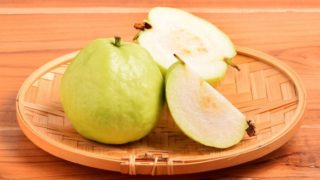 A close-up shot of guavas placed against a wooden background