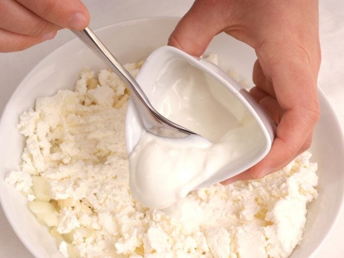Close-up of a person adding cream to cheese.