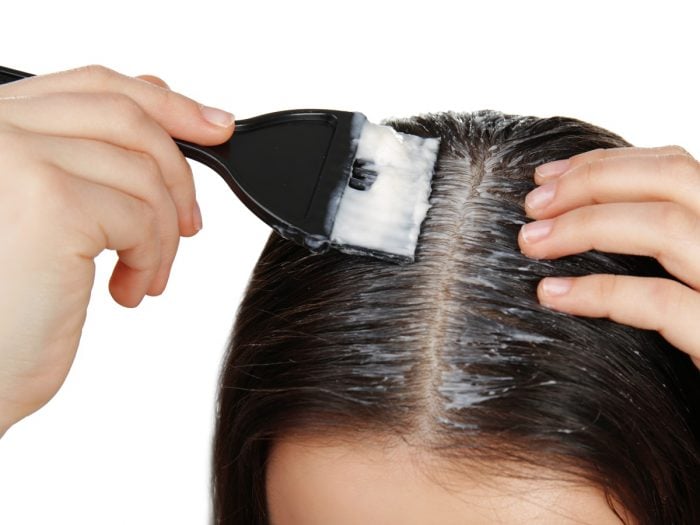 Close up of woman applying coconut oil on her scalp with a brush