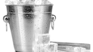 A bucket full of ice next to a steel tong
