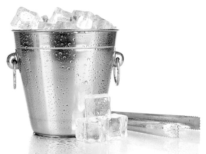 A bucket full of ice next to a steel tong