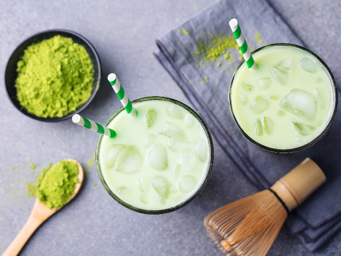 Matcha green tea ice latte with matcha powder and bamboo whisk, top view