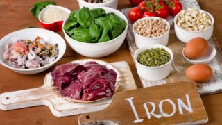 Iron rich foods (meat, fish, nuts, rice, pulses, cereals, eggs, tomatoes) on a wooden table