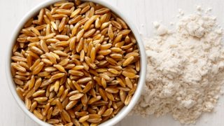 Kamut grains in a big wooden bowl and some flour around