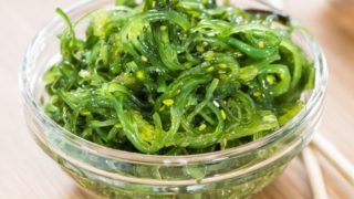 A bowl of cooked kelp on a wooden table