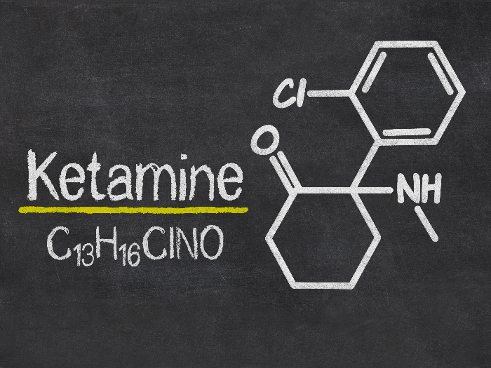 Ketamine is written on a blackboard with the chemical equation
