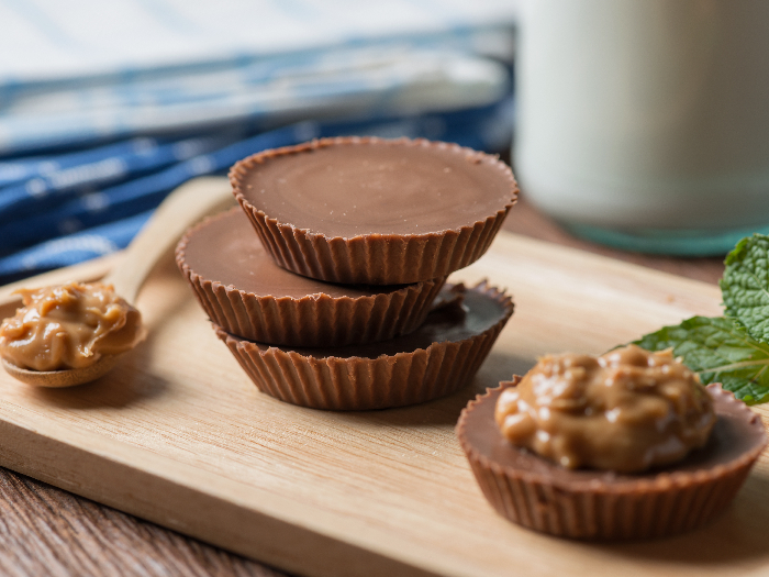 Homemade peanut butter cup, dark chocolate with caramel and bottle of milk.