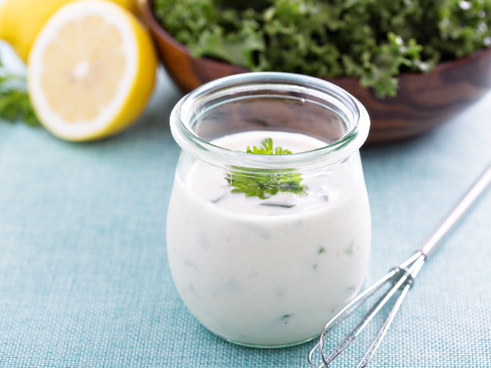 ranch dressing in a glass bottle next to a green salad with a lime half