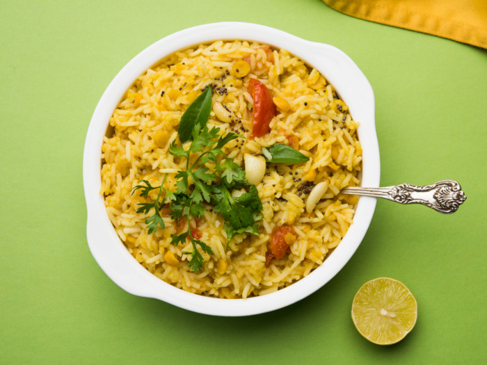 A plate of warm khichdi garnished with coriander and bay leaves on a light green placemat