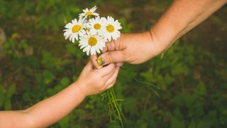 A kid showing a random act of kindness by sharing flowers with a grown up lady