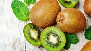Sliced kiwi fruit with a whole kiwi on a wooden table