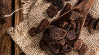 A wooden spoon of dried kola nuts kept on a jute cloth