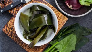 Wet soaked kombu seaweed leaves in a bowl with other fresh vegetables
