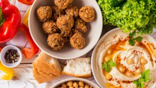 Kosher food including deep fried matzo balls, chickpea hummus, bread, and bell peppers