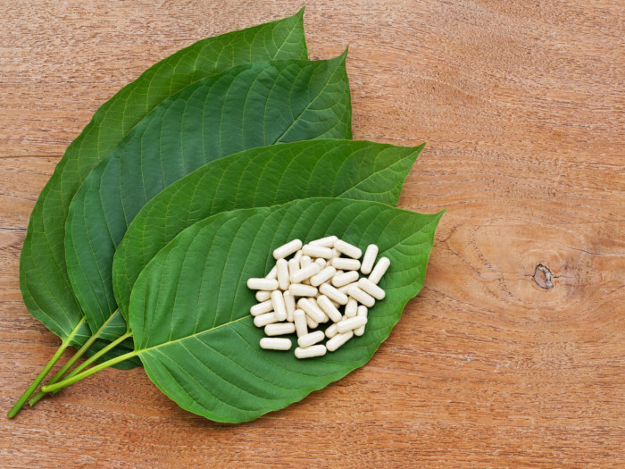 Kratom leaves and pills on a wooden counter
