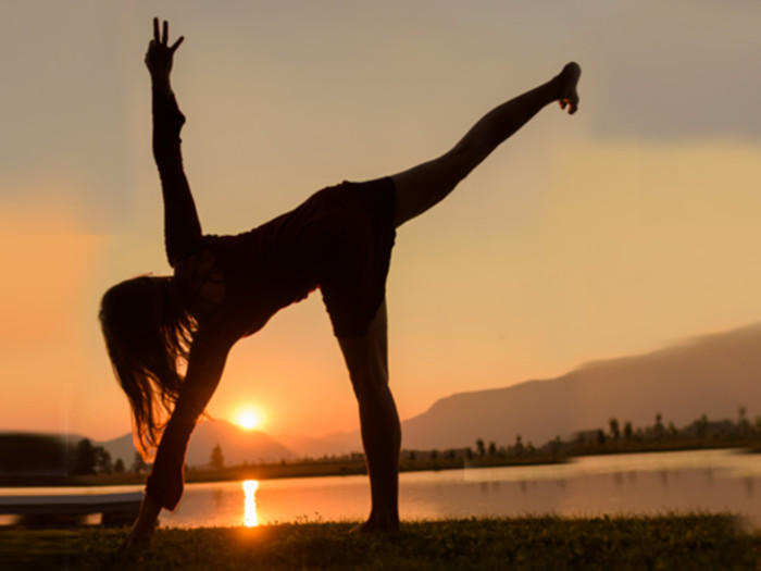 A woman doing yoga in front of the rising sun