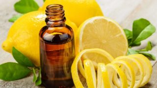 A bottle of lemon oil with peeled lemon and whole lemons