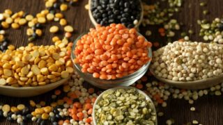 An assortment of various lentils in bowls and spoons