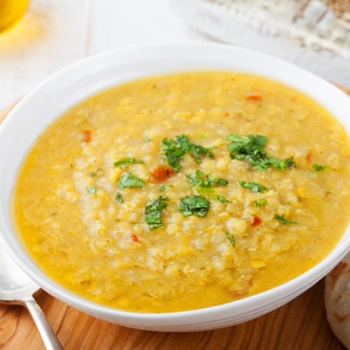 Lentil soup with pita bread in a ceramic white bowl on a wooden background