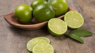 Juicy limes-sliced and whole, on a wooden table