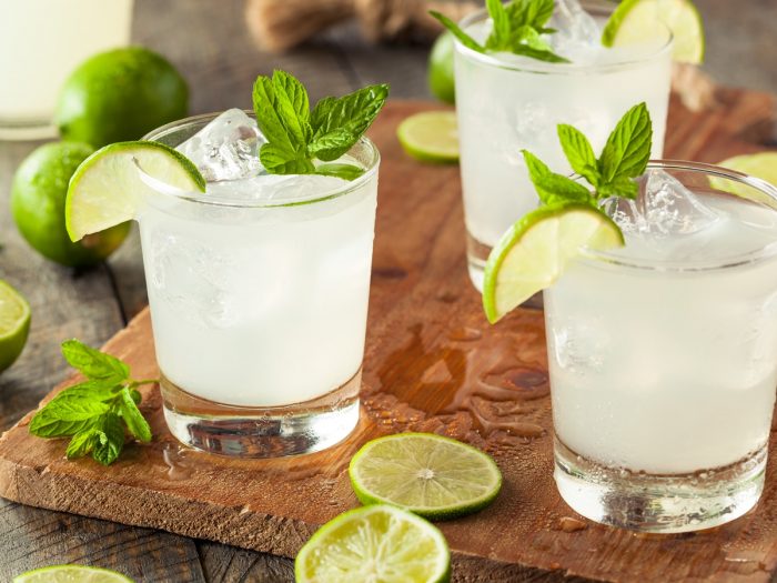 Limeade in glasses garnished with mint and lime slices, with whole limes in the background