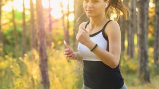 A woman jogging, with earphone on attached to her phone