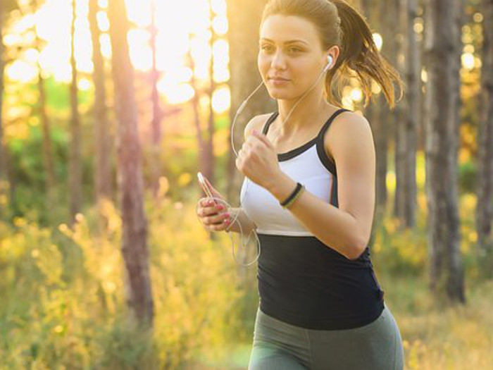 A woman jogging, with earphone on attached to her phone