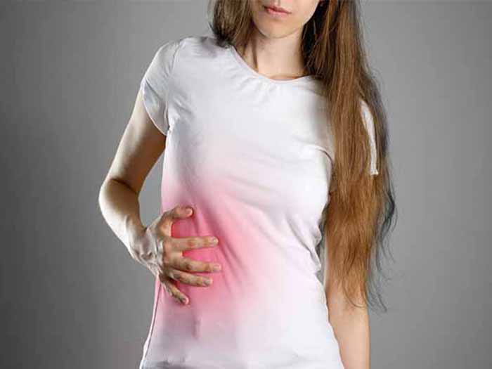 A woman holding the right side of her belly where the liver resides