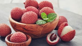 A wooden bowl filled with lychee and kept on a wooden table