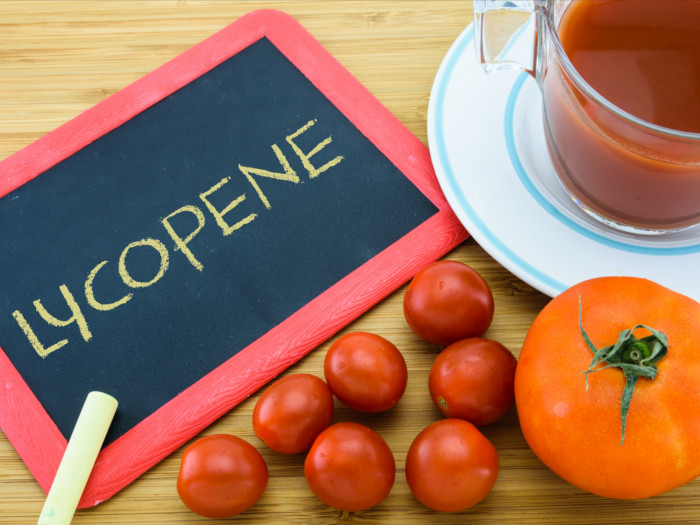 Lycopene written on a small blackboard with chalk alongside tomatoes and tomato juice