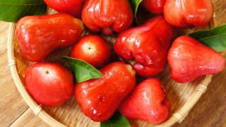 Fresh bright red Malay apples in a round cane tray