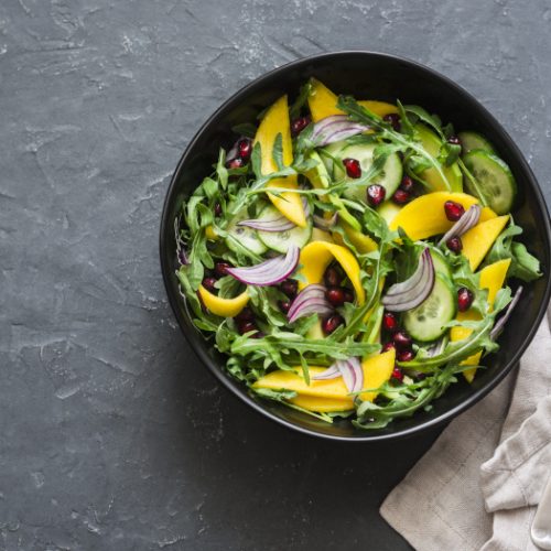 Tropical mango, avocado, cucumber, arugula salad on a plate