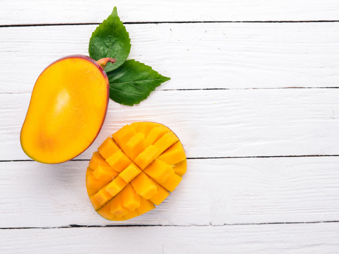 A flat lay picture of sliced mangoes against a white background