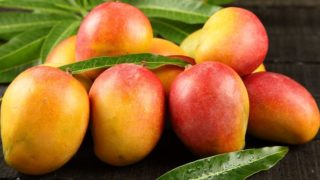 Mangoes with a reddish-yellow skin on a wooden counter