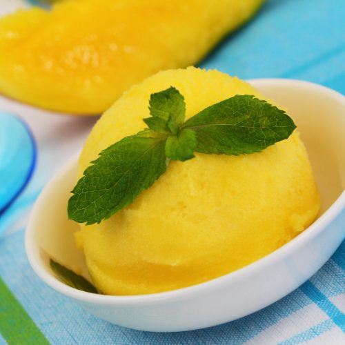 A scoop of mango sorbet garnished with mint.