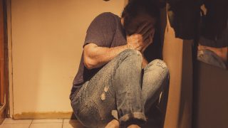 Man with acute depression and PTSD sitting in corner with fear