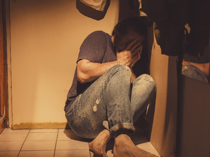 Man with acute depression and PTSD sitting in corner with fear