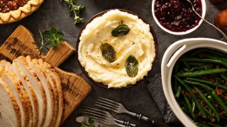 A flatlay picture of mashed potatoes with butter and sage, side dish for Thanksgiving or Christmas dinner, kept next to asparagus, baked beans and turkey slices.
