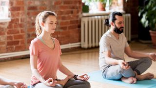 A man and woman meditating indoors.