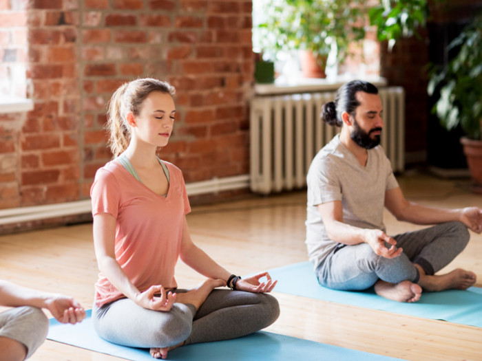 A man and woman meditating indoors.