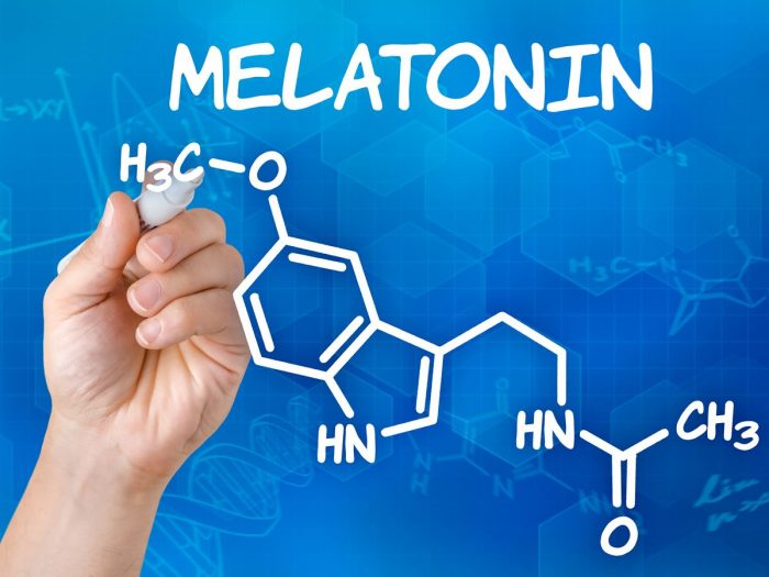 A hand drawing the chemical formula of melatonin