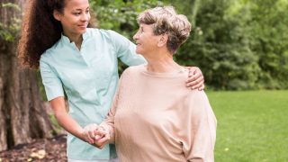 Elder woman and caregiver walking in the park