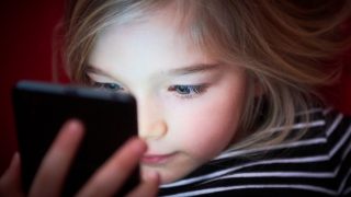 Cute girl playing game or watching movie in smartphone