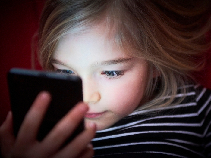 Cute girl playing game or watching movie in smartphone