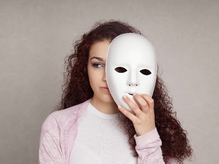 Sad girl hiding her real emotions behind a mask