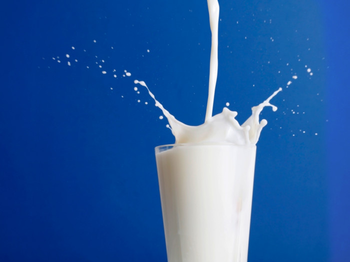 Milk being poured with a splash into a glass on a blue background