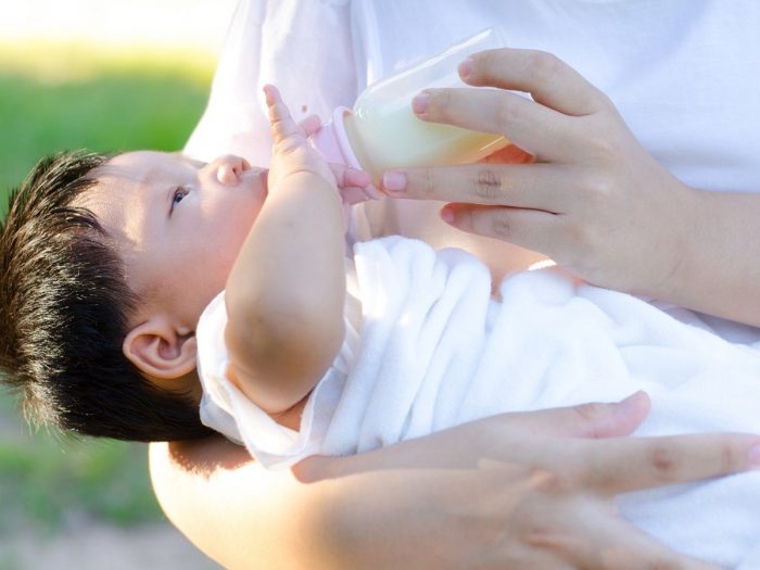 A person feeding milk to a baby