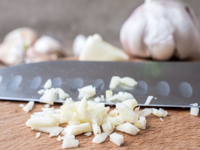 Minced garlic on a cutting board on a background of chef knife