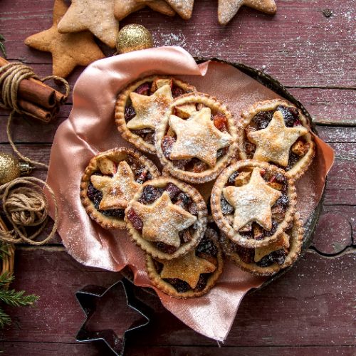 Mince pies in a vintage old plate with christmas decoration on wooden background