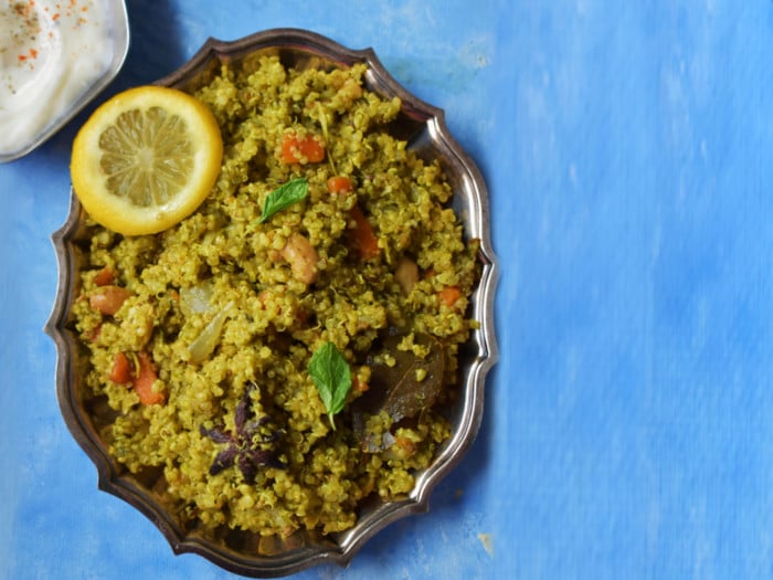 Mint quinoa atop a blue table beside a bowl of curd